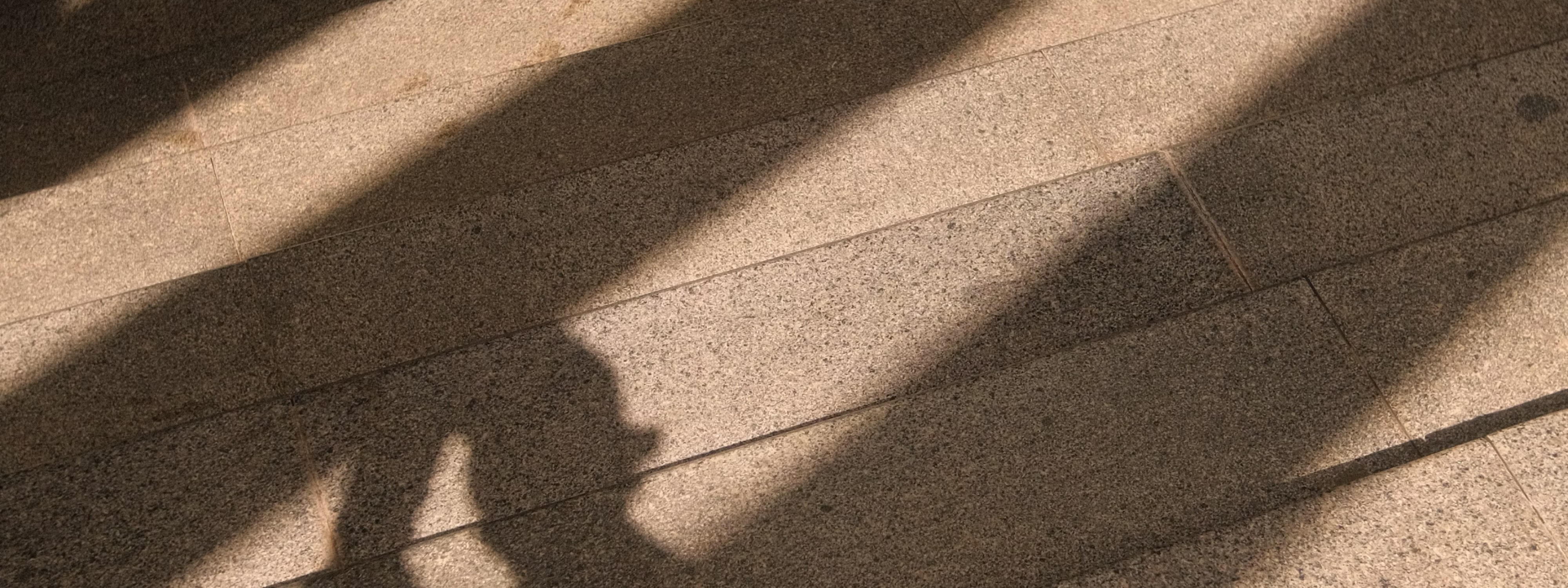 Shadows cast on textured stone or tile floor with diagonal light